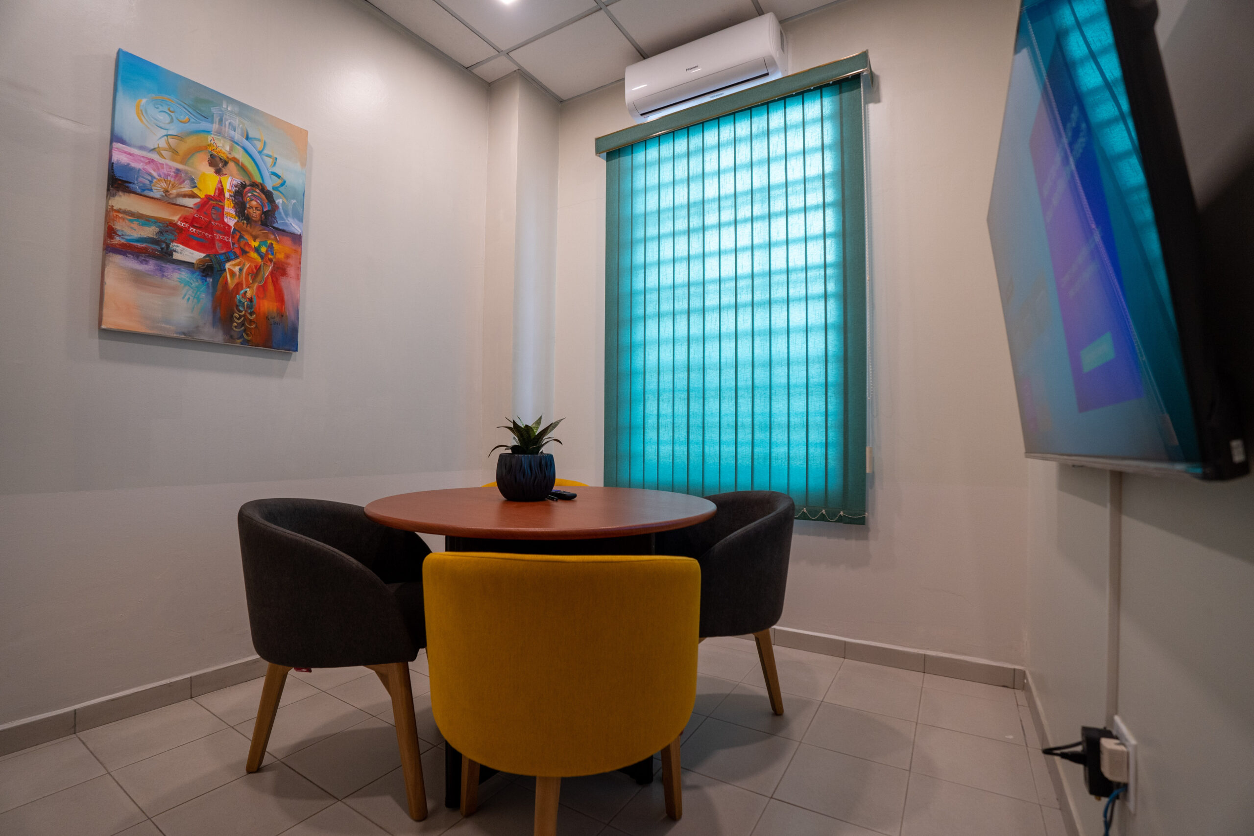 Virtual Office in Suriname with small meeting room with a round table, three chairs, and a wall-mounted TV.